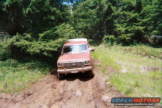 Red 1980s Ford Bronco on muddy trail