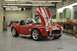 1996 Ford Bronco - A red convertible sports car with racing stripes sits in a workshop, its hood open.