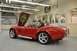 1996 Ford Bronco - A red convertible sports car is parked in a garage with its hood open, revealing custom cobra artwork.