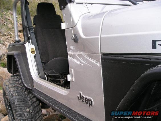 Silver Jeep Wrangler side view, showing door and seat. Scratches on the body