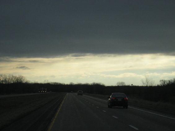 Cars driving on a highway under a dark, cloudy sky