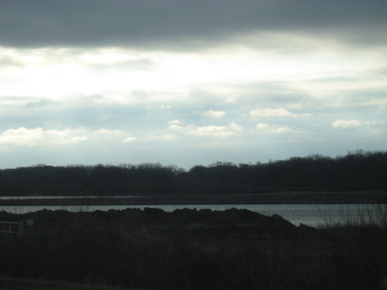 cloudy sky over a dark landscape with a body of water