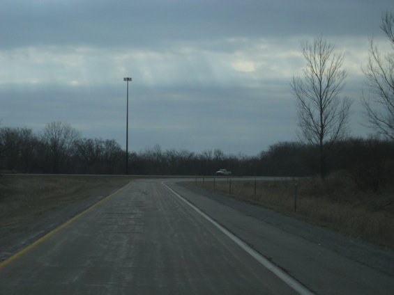 White SUV driving on a highway under a cloudy sky