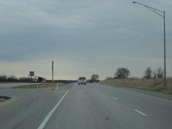 White van driving on a highway under a cloudy sky