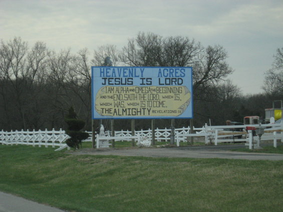 Sign reads 'HEAVENLY ACRES JESUS IS LORD I AM ALPHA AND OMEGA THE BEGINNING AND THE END, SAITH THE LORD, WHICH IS, WHICH WAS, WHICH IS TO COME, THE ALMIGHTY REVELATIONS 1:8'