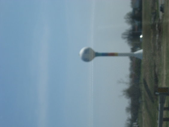 Water tower with rainbow stripe against blue sky