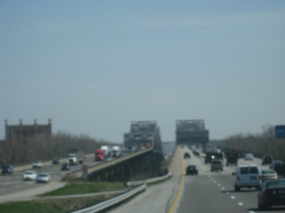 Highway traffic on a bridge with industrial buildings in the distance