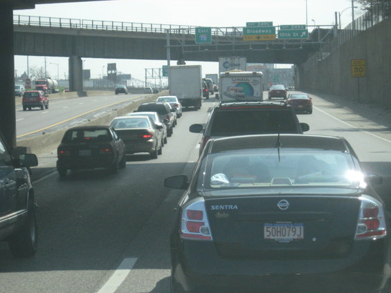 Traffic jam on a highway with multiple cars and trucks, overhead signs visible