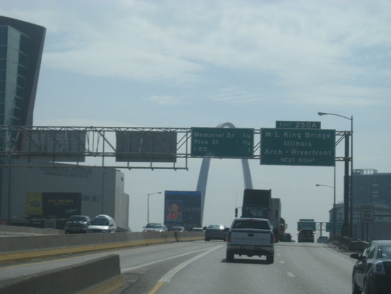 Highway traffic with St. Louis Arch in background and directional signs for ML King Bridge and Memorial Dr