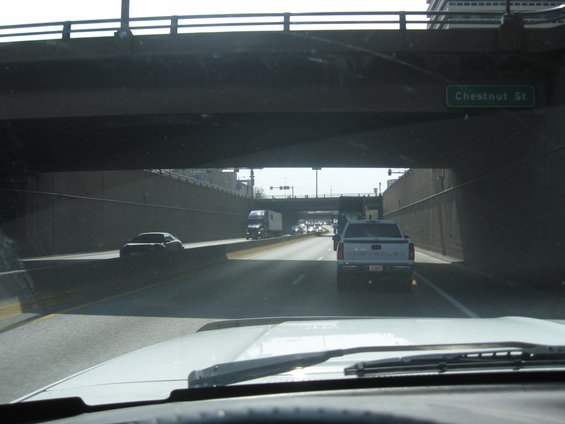 View from inside a vehicle looking out at highway traffic under an overpass with a Chestnut St sign