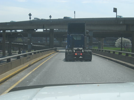 Rear view of blue semi-truck cab on highway overpass