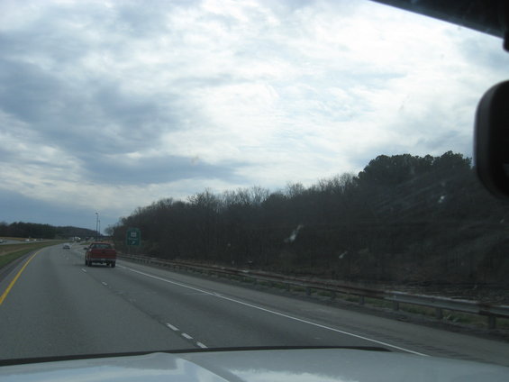 Red pickup truck driving on a highway under a cloudy sky