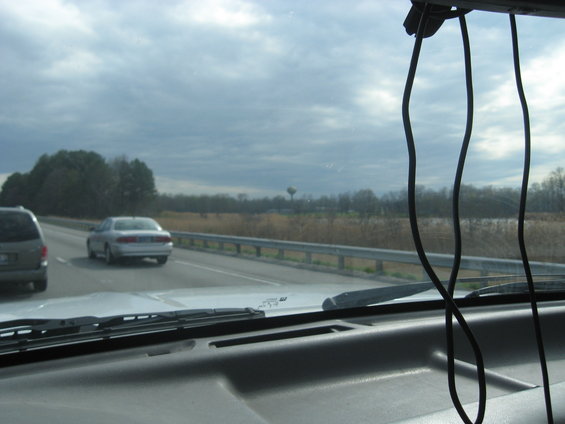View from inside a vehicle looking out at a highway with another car and a van driving
