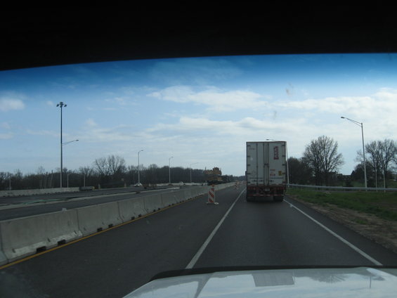 Semi-trailer truck ahead on highway, with concrete barriers and streetlights