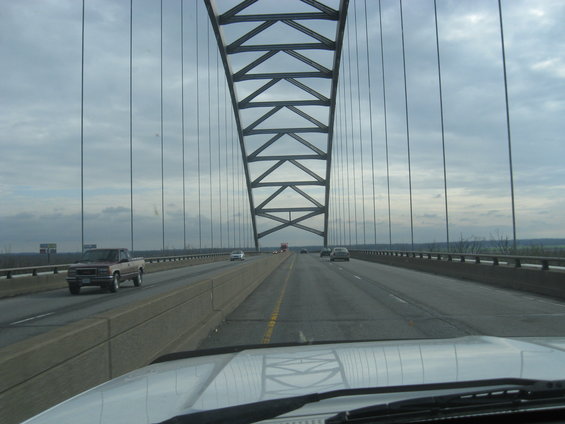Pickup truck driving on a suspension bridge under a cloudy sky