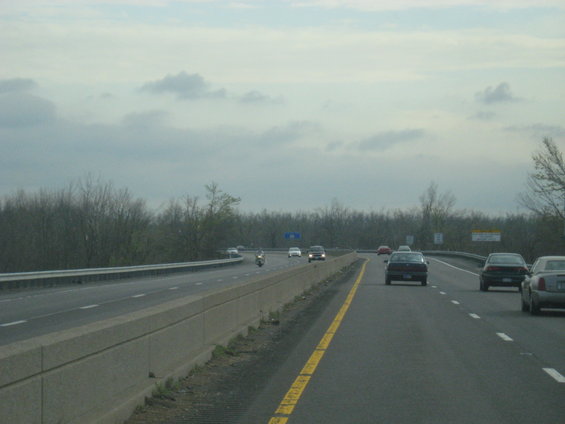 Cars and a motorcycle on a highway under a cloudy sky