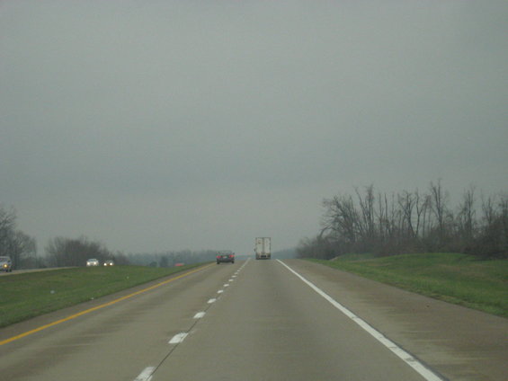 Highway driving scene with a truck and cars under an overcast sky