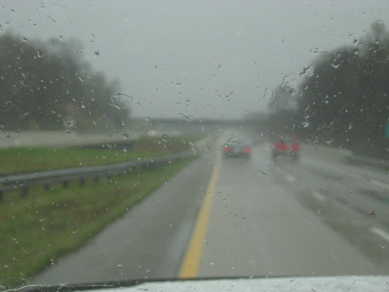 Cars driving on a wet highway under a cloudy sky