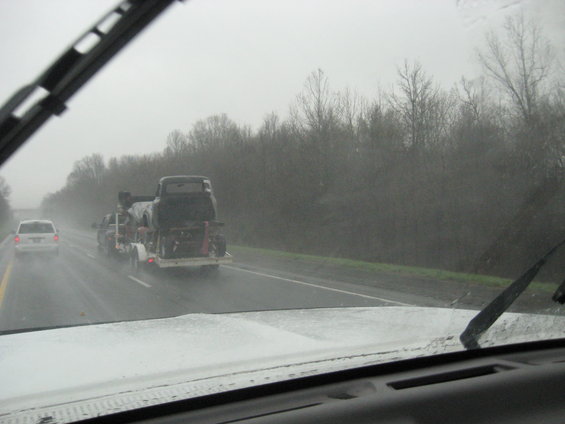 Black pickup truck on trailer, seen from behind on a wet highway