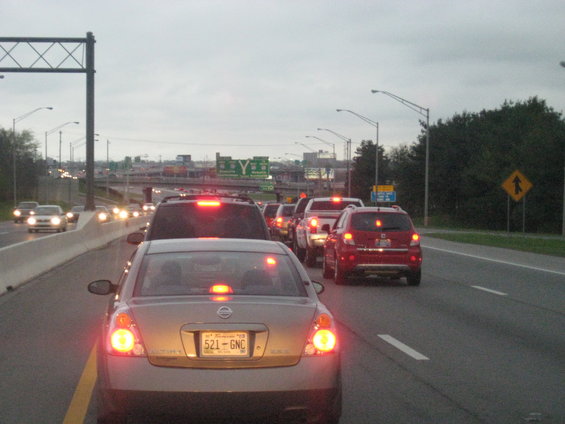 Traffic jam on a highway with multiple cars, including a gold sedan and a red SUV