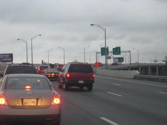 Cars stuck in traffic on a cloudy day, with highway signs overhead