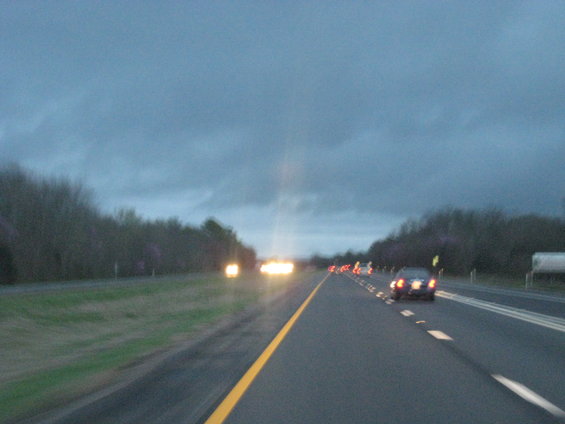 Driving on a highway with multiple cars visible under a cloudy sky at dusk