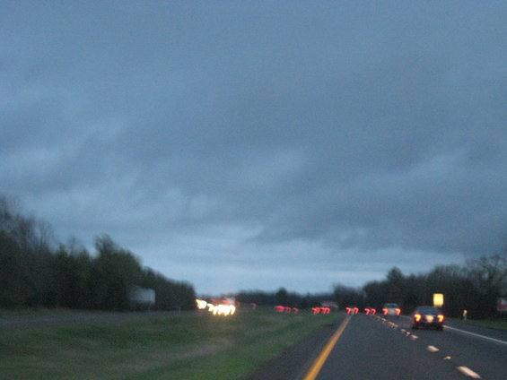 Highway traffic at dusk with blurred headlights and taillights visible on a two-lane road