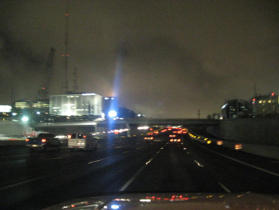 Highway traffic at night with city lights and buildings in the background