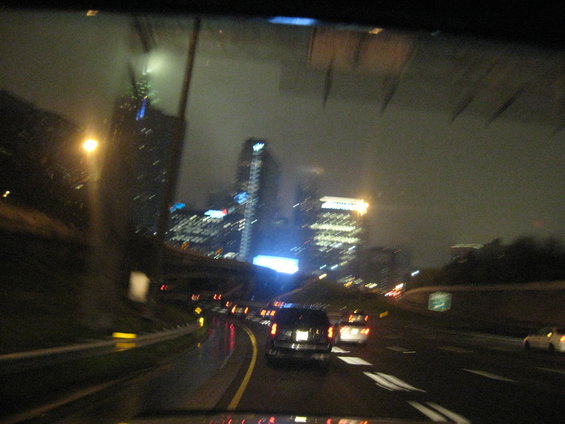 Highway driving at night with city lights and rain on windshield