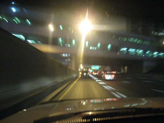 View from inside a vehicle driving on a highway at night, with streetlights and other cars visible