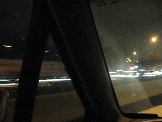 Car interior looking out at a blurry highway at night with streaks of light from traffic
