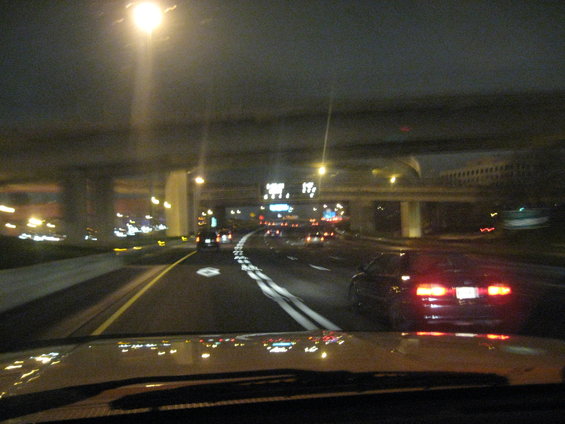 Highway at night with overhead bridge and car taillights