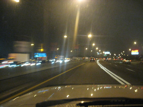 View from inside a vehicle looking out at a busy highway at night with many cars and trucks