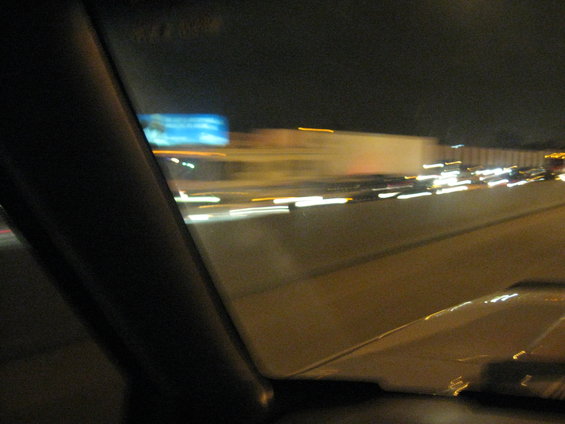 View from inside a car at night, looking out at highway traffic with blurred lights