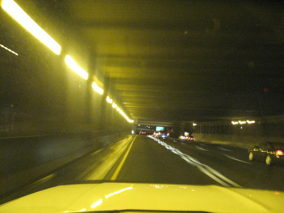 driving through a tunnel at night, lights on ceiling, cars on road ahead