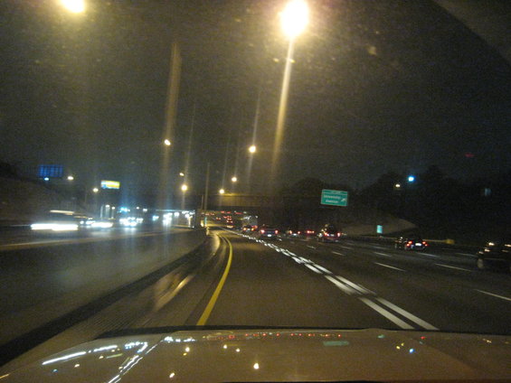 Highway traffic at night with streetlights and car headlights reflecting on the wet road