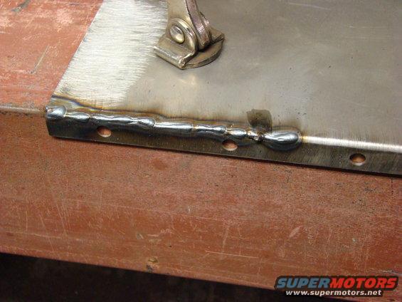 Welding on a metal panel with visible weld beads and drilled holes