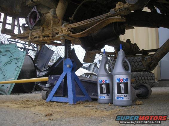 vehicle rear axle assembly on jack stands with two bottles of Mobil 1 gear oil