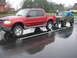 1987 Suzuki Samurai - A red Ford Explorer Sport Trac tows a green Suzuki Samurai on a wet day.