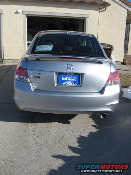 Silver sedan rear view, showing a spoiler and a blue license plate frame