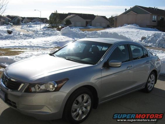 Silver sedan parked on a driveway with snow piles in the background