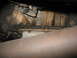 1995 Ford C-350 (Centurion Conversions) - Close-up view of a vehicle's transmission pan and casing, with visible oil stains and a section of exhaust pipe.