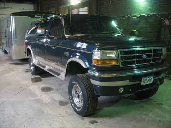 Dark blue Ford SUV with a trailer hitched to it. The SUV has a chrome grille and running boards