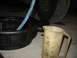 1995 Ford C-350 (Centurion Conversions) - Fluid being drained into a pan and measured in a cup, likely part of vehicle maintenance.