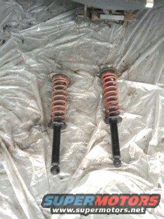 Two red coilover shock absorbers on a white tarp