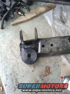 close-up of a car suspension part, looks like a control arm or similar, on a concrete surface