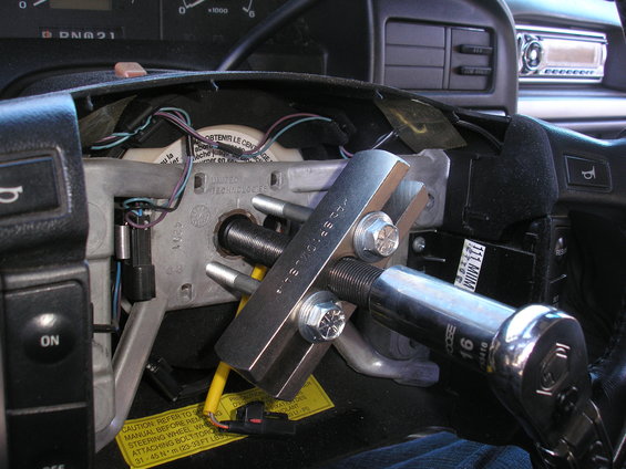 Steering wheel puller tool attached to steering column with bolts and socket wrench