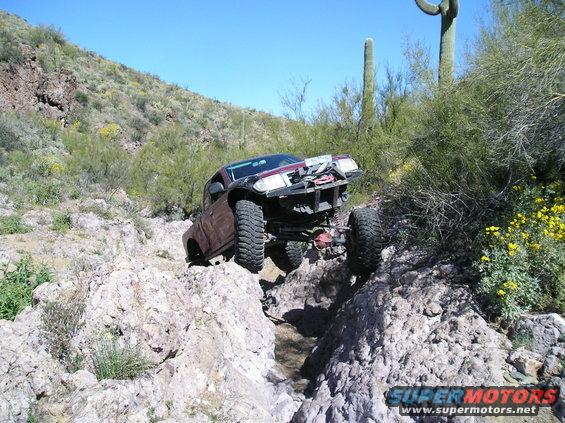 pickup truck crawling over rocks in a desert landscape
