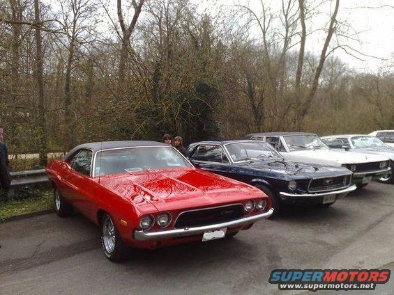 Red muscle car parked in front of other classic cars