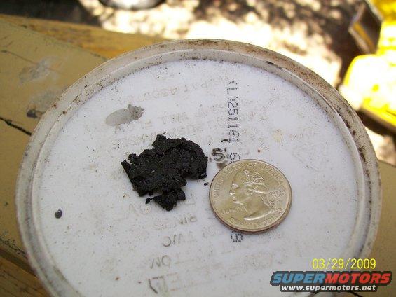 Oil sludge on white lid with quarter for scale